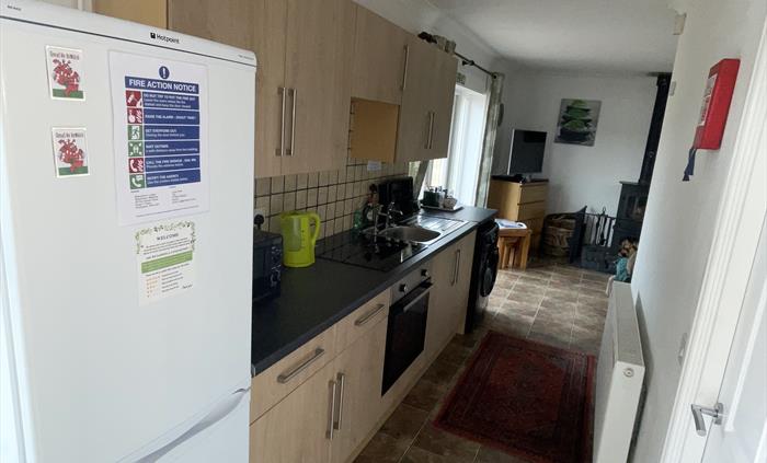 Shows fridge freezer, kitchen wall and base cabinets, ceramic hob, single electric oven, sink, washing machine, radiator and French doors.